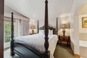 Bedroom featuring lofted ceiling, multiple windows, carpet floors, access to exterior, and arched walkways