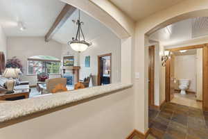 Hall with baseboards, arched walkways, and stone tile floors