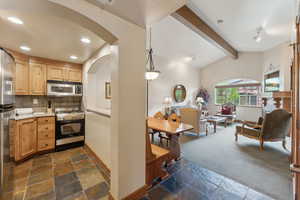 Kitchen featuring appliances with stainless steel finishes, stone tile flooring, arched walkways, tasteful backsplash, and recessed lighting