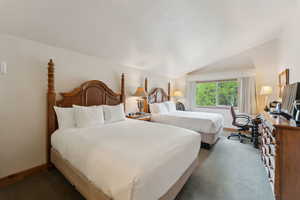 Carpeted bedroom featuring lofted ceiling and baseboards