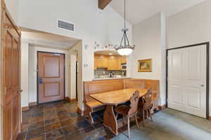 Dining room featuring baseboards, high vaulted ceiling, arched walkways, dark stone finish flooring, and beamed ceiling