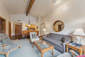 Carpeted living room with beam ceiling and high vaulted ceiling