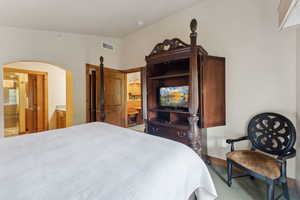 Carpeted bedroom featuring arched walkways