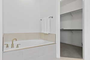 Full bath featuring a walk in closet and a garden tub
