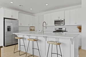 Kitchen featuring stainless steel appliances, white cabinetry, light countertops, and recessed lighting