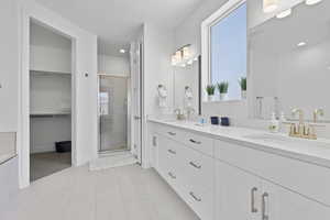 Full bath featuring a shower stall, tile patterned flooring, recessed lighting, double vanity, and a walk in closet