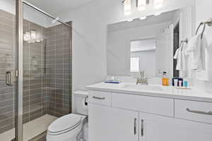 Full bath with a stall shower, toilet, and vanity