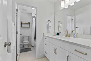Bathroom featuring vanity, tile patterned floors, toilet, baseboards, and shower / bath combo