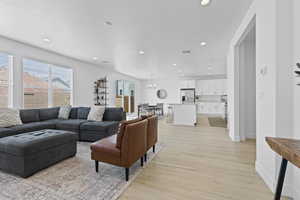 Living room featuring healthy amount of natural light, light wood-type flooring, recessed lighting, baseboards, and a chandelier