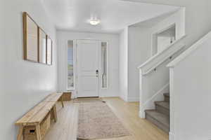 Entrance foyer featuring light wood finished floors, stairway, and baseboards