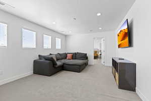 Living room with recessed lighting, light colored carpet, baseboards, and a textured ceiling