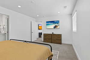 Bedroom featuring light carpet, recessed lighting, baseboards, and ensuite bath