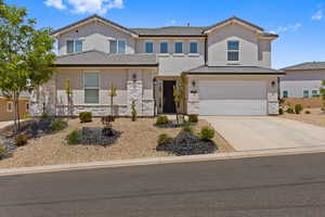 View of front of house featuring stone siding, a garage, concrete driveway, and stucco siding