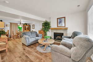 Living room with a tiled fireplace, a chandelier, and light wood-style floors
