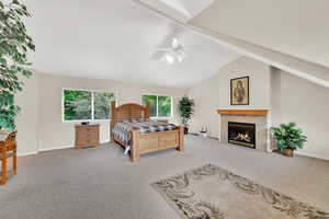 Carpeted bedroom with baseboards, a tiled fireplace, and a ceiling fan