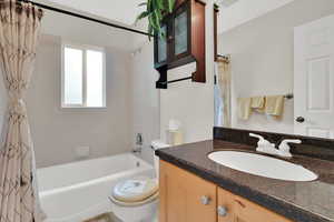 Bathroom featuring toilet, shower / bath combination with curtain, and vanity