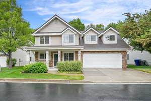 View of front of house with concrete driveway, covered porch, a shingled roof, and stone siding