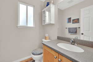 Half bath featuring toilet, vanity, and baseboards
