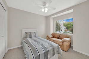Bedroom with light colored carpet, baseboards, and ceiling fan