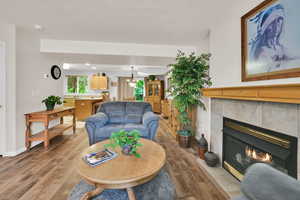 Living room with wood finished floors, a tile fireplace, and baseboards
