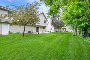 View of grassy yard featuring a patio area and central AC