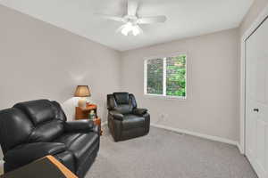 Living area with carpet, baseboards, and ceiling fan