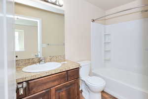 Bathroom featuring toilet, tub / shower combination, vanity, and wood finished floors