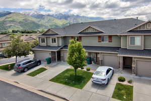 View of front of home featuring driveway, an attached garage, a mountain view, and a shingled roof