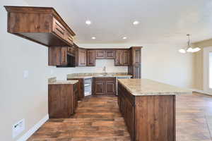 Kitchen featuring a sink, a center island, baseboards, a chandelier, and recessed lighting