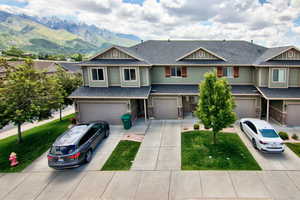 View of front of home featuring a garage, a shingled roof, a mountain view, driveway, and a front lawn