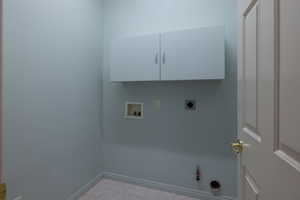 Laundry room with washer hookup, electric dryer hookup, hookup for a gas dryer, baseboards, and light tile patterned floors