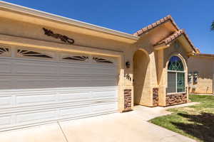 View of front of house featuring concrete driveway, stucco siding, an attached garage, a tile roof, and stone siding