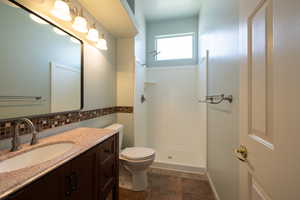 Full bathroom featuring a shower stall, toilet, vanity, and tasteful backsplash