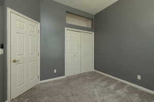 Unfurnished bedroom with carpet floors, a closet, and baseboards