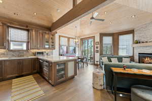 Kitchen with a sink, light countertops, appliances with stainless steel finishes, a peninsula, and a stone fireplace
