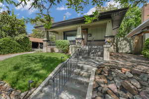 View of front of home featuring covered porch, a front lawn, stone siding, and board and batten siding.