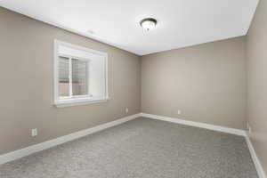 Bedroom with egress window, carpet and baseboards.