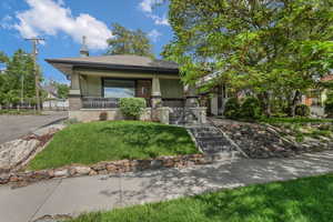 View of front of house with covered porch, a front lawn, and roof with shingles.