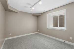 Bedroom with carpet flooring, baseboards, and track lighting.