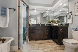Bathroom featuring toilet, recessed lighting, a shower stall, vanity, and a freestanding bath.