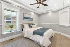 Bedroom with carpet floors, a raised ceiling, crown molding, recessed lighting, and baseboards.
