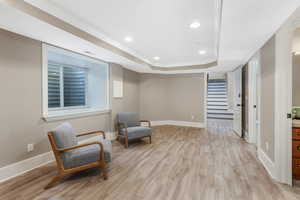 Unfurnished room featuring a raised ceiling, stairway, baseboards, light wood-style flooring, and recessed lighting.