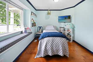 Bedroom with multiple windows, ornamental molding, baseboards, and wood finished floors