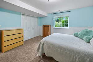 Carpeted bedroom featuring a wainscoted wall and a closet