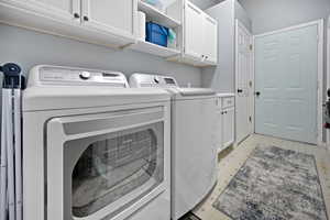 Laundry room featuring cabinet space, washing machine and clothes dryer, and light floors