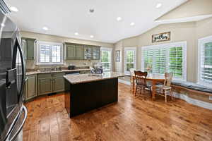 Kitchen featuring stainless steel fridge with ice dispenser, a sink, light wood-style floors, a kitchen island, and lofted ceiling