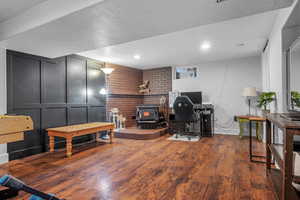 Home office featuring wood finished floors, a wood stove, a textured ceiling, and recessed lighting