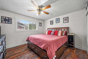 Bedroom featuring baseboards, dark wood-style floors, a textured ceiling, and ceiling fan