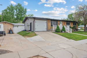 Ranch-style house featuring a garage, concrete driveway, brick siding, a porch, and a gate