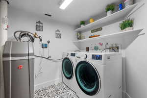 Laundry room featuring separate washer and dryer, tile patterned floors, and baseboards